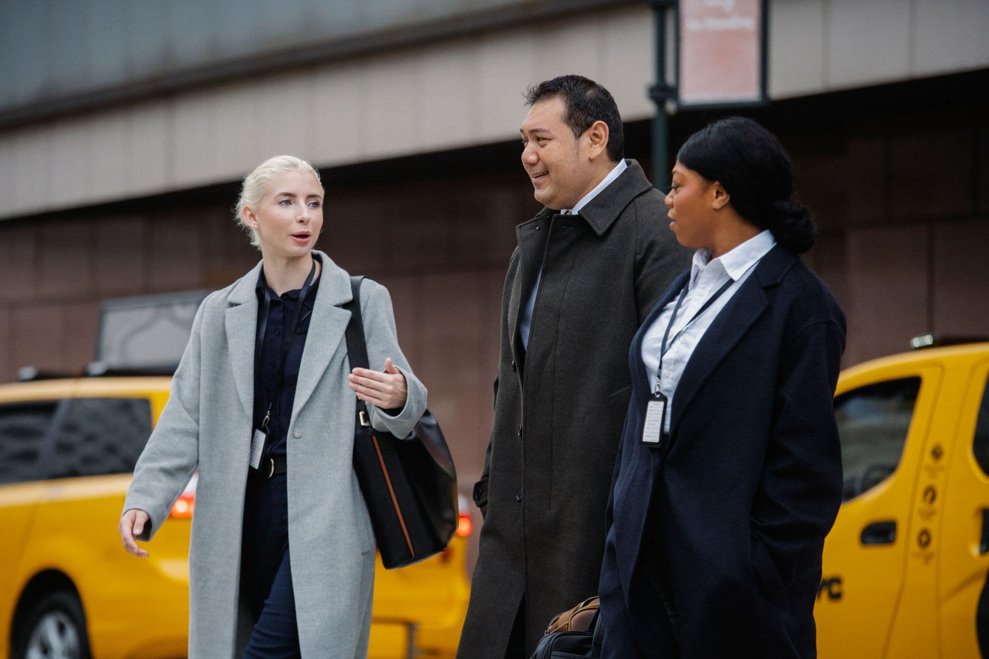 Three professionals talking as they walk through a city